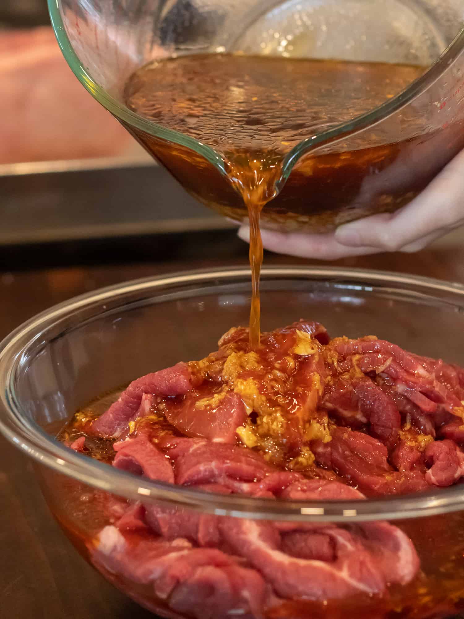 Pouring the Asian marinade mixture all over the sliced beef.