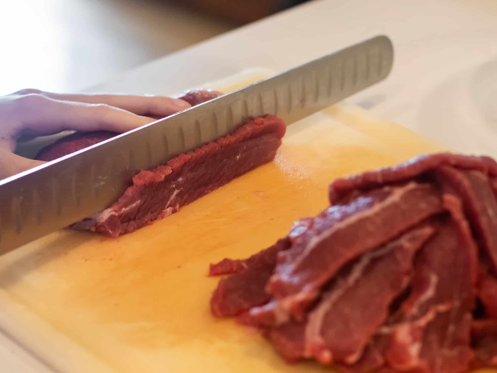 Slicing the beef round roast into thin strips.