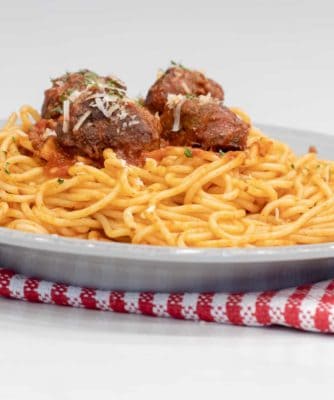 A plate of spaghetti topped with four meatballs and sauce.
