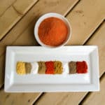 A plate with colourful spices piled next to each other.