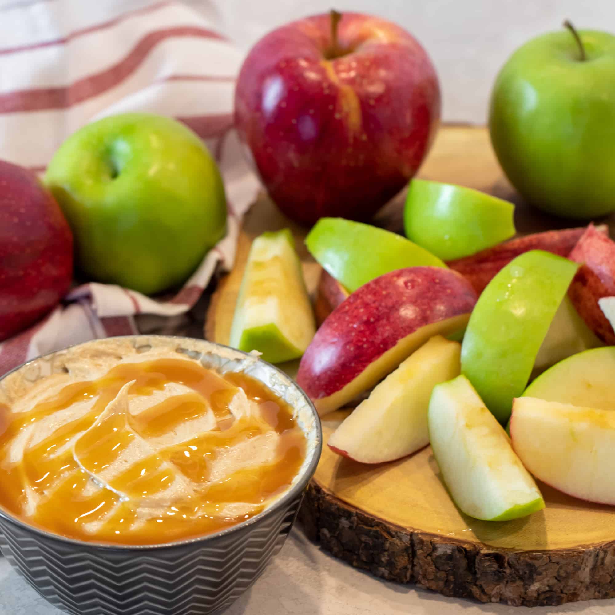 Overhead picture of a pile of sliced apples next to a bowl of caramel spread.