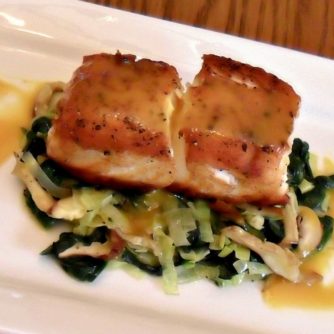 A pan seared filet of halibut served on a bed of sauteed leeks, spinach and oyster mushrooms drizzled with a honey mustard sauce.