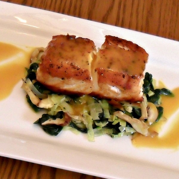 A pan seared filet of halibut served on a bed of sauteed leeks, spinach and oyster mushrooms drizzled with a honey mustard sauce.