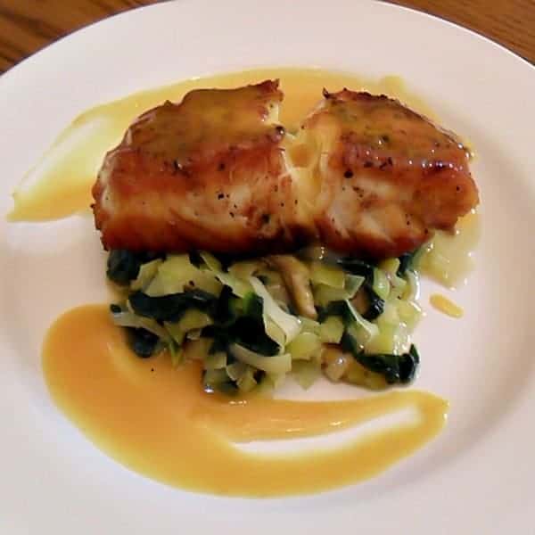 A pan seared filet of halibut served on a bed of sauteed leeks, spinach and oyster mushrooms drizzled with a honey mustard sauce.