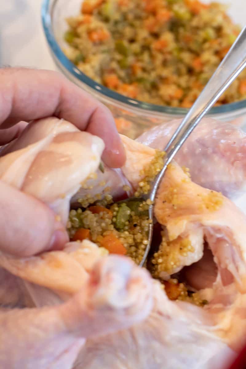 Spooning the stuffing into the open cavity of the chicken.