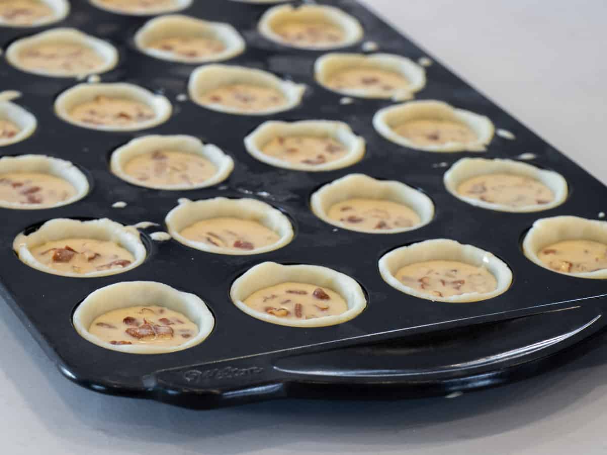 A tray of mini tarts ready to be baked in the oven.