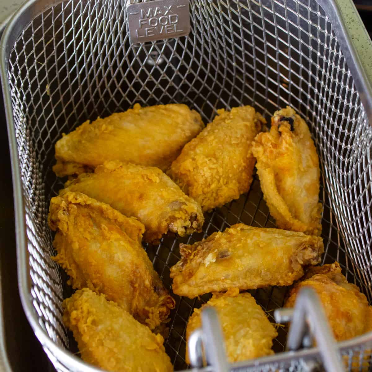 Wings out of the fryer and draining in the basket.