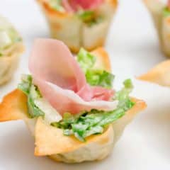 This wonton cup recipe is a snap to make and filled with caesar salad, parmesan cheese and a slice of prosciutto. They look amazing and taste delicious!