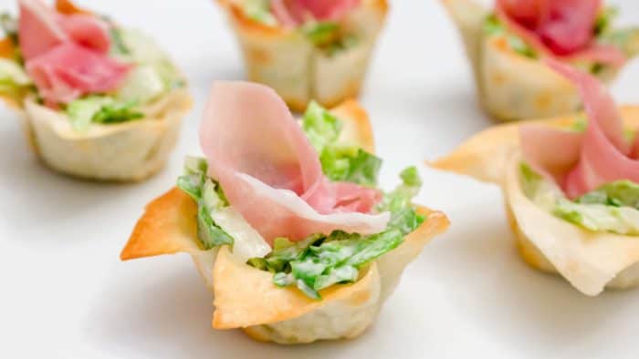 This wonton cup recipe is a snap to make and filled with caesar salad, parmesan cheese and a slice of prosciutto. They look amazing and taste delicious!