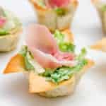 This wonton cup recipe is a snap to make and filled with caesar salad, parmesan cheese and a slice of prosciutto. They look amazing and taste delicious!