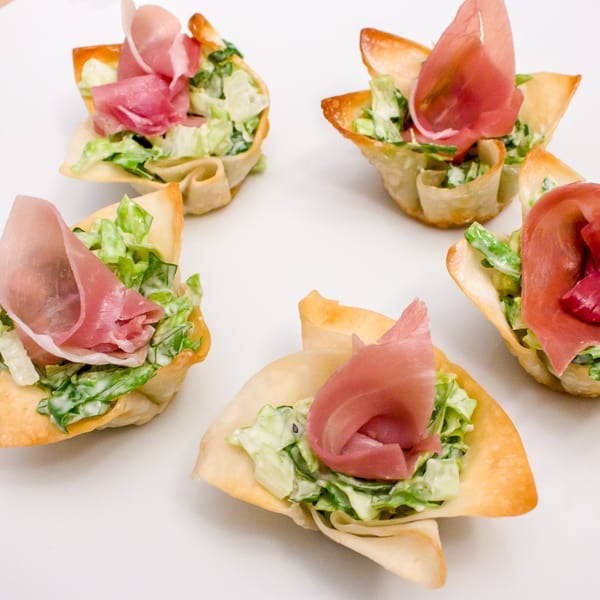 This wonton cup recipe is a snap to make and filled with caesar salad, parmesan cheese and a slice of prosciutto. They look amazing and taste delicious!