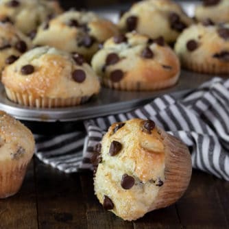 Muffin tray with chocolate chip muffins with a striped tea towel