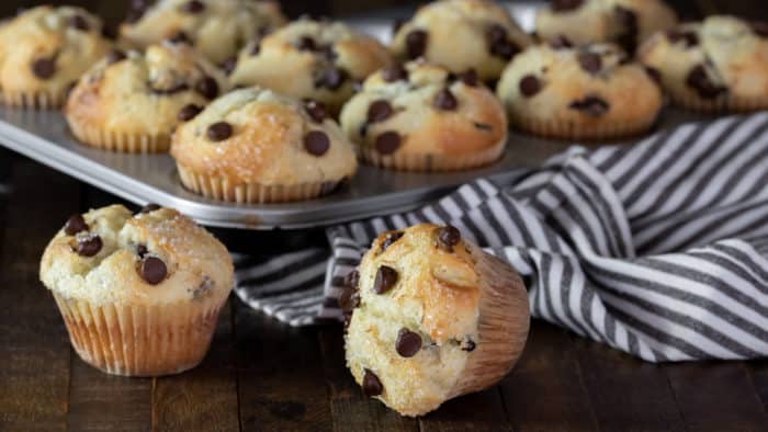 Muffin tray with chocolate chip muffins with a striped tea towel
