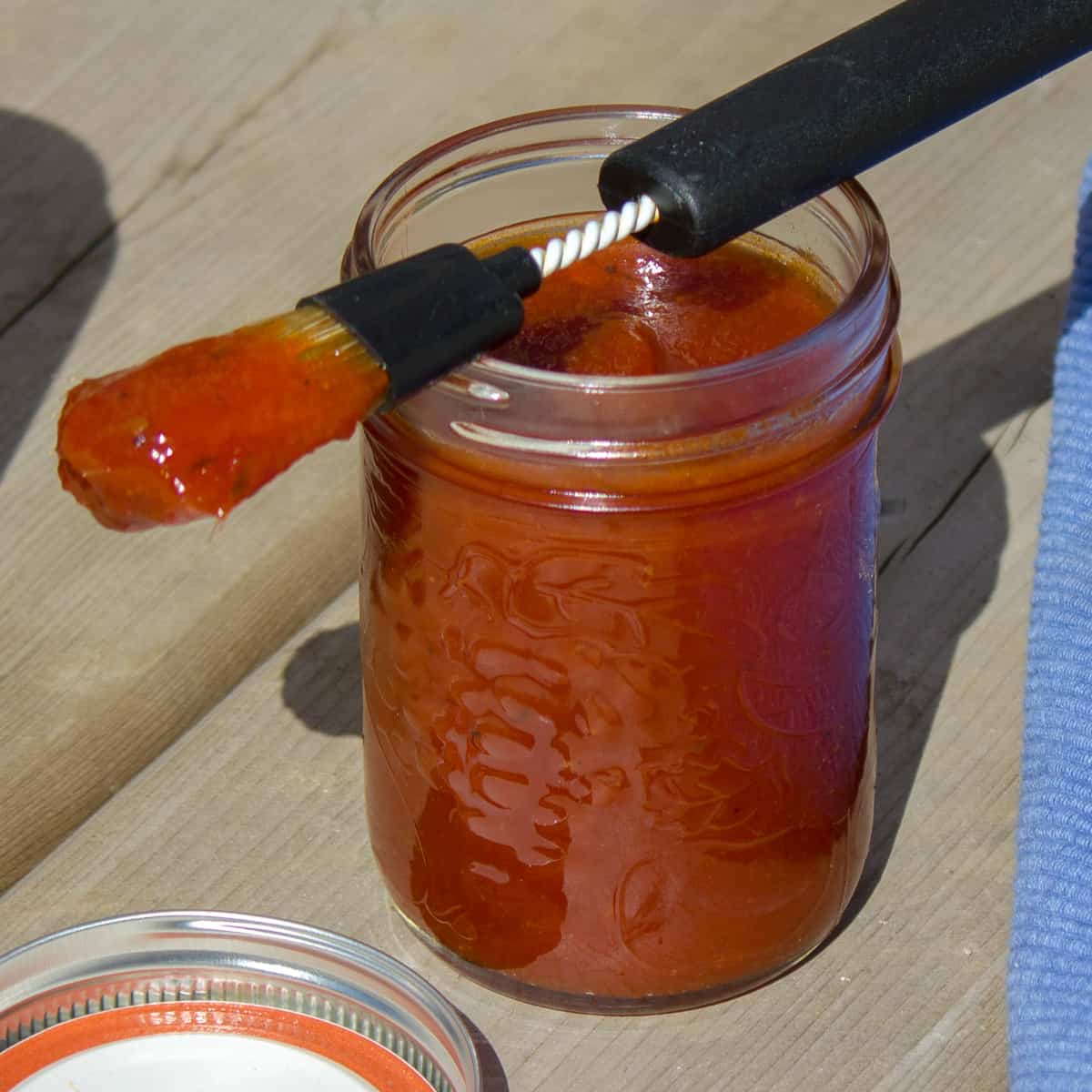 A brush with BBQ sauce resting on a jar.