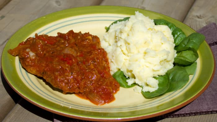 Swiss steak takes a cheap and tough cut of beef like round or sirloin steak (cube or minute), which is then braised in stewed tomatoes and other vegetables.