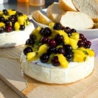 Easy recipe for how to plank grill brie cheese. Then topped with a fresh salsa of blueberries, mango, jalapeno, lime juice and a drizzle of honey.