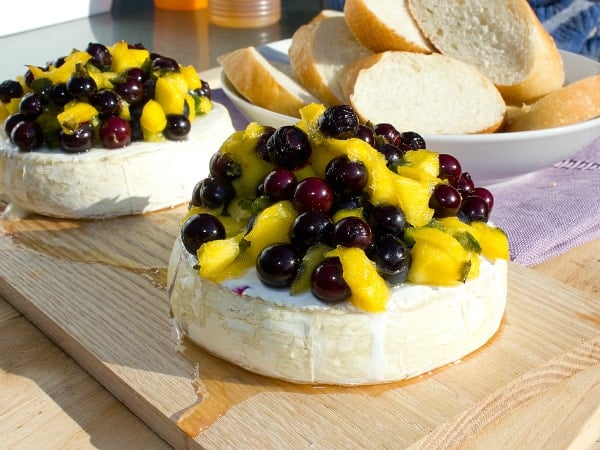 Easy recipe for how to plank grill brie cheese. Then topped with a fresh salsa of blueberries, mango, jalapeno, lime juice and a drizzle of honey.