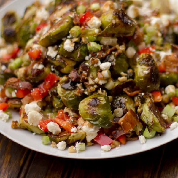 Roasted Brussels sprout salad recipe with bacon, walnuts, feta cheese, green onions, re peppers and a balsamic vinaigrette. Instructions for how to roast brussels sprouts.