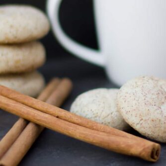 Round cookies piled together and next to cinnamon sticks.