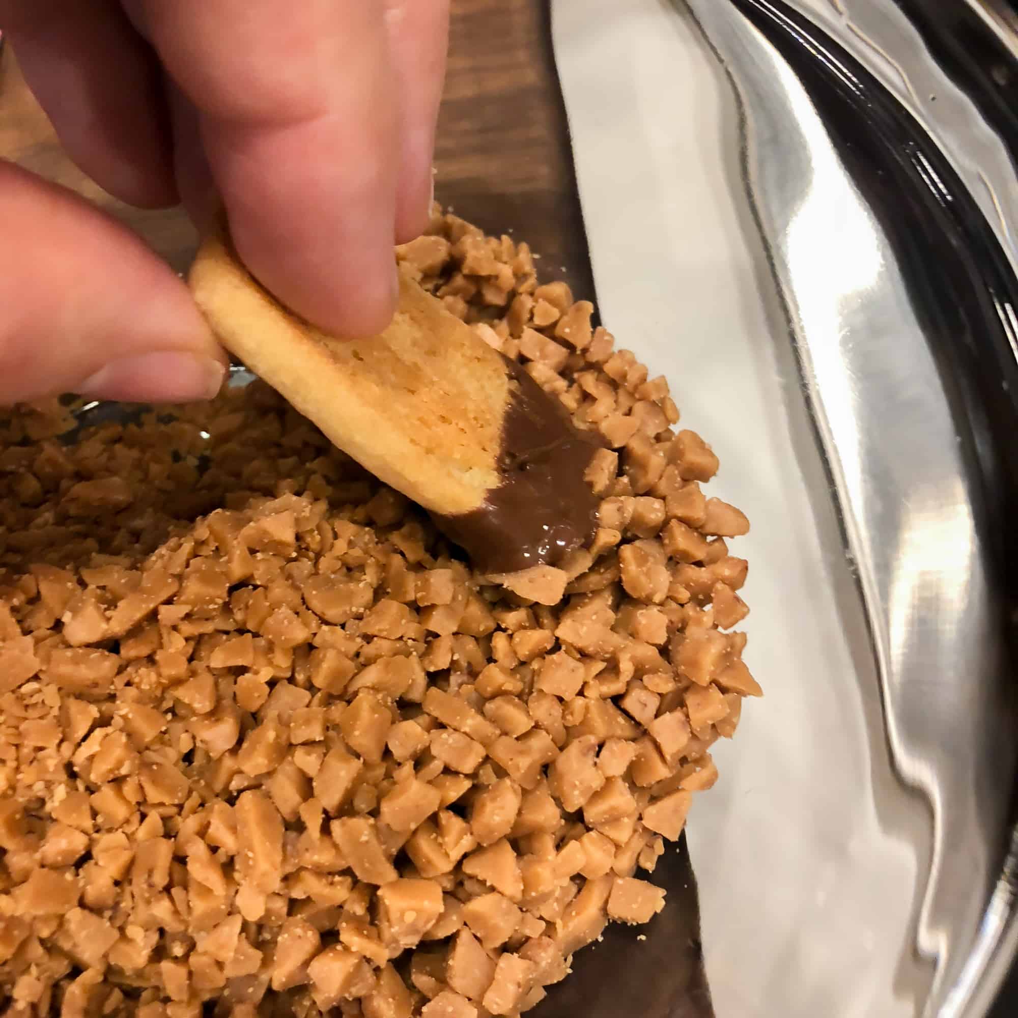 Right after the cookie is dipped in melted chocolate, dip it right into some skor butter crunch bits.