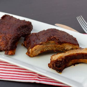 Slow braised ribs with rub and bourbon bbq sauce recipe. Cook in the oven or crock pot / slow cooker. Meat is fall off the bone tender.