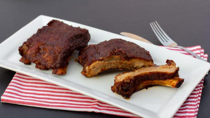 Slow braised ribs with rub and bourbon bbq sauce recipe. Cook in the oven or crock pot / slow cooker. Meat is fall off the bone tender.