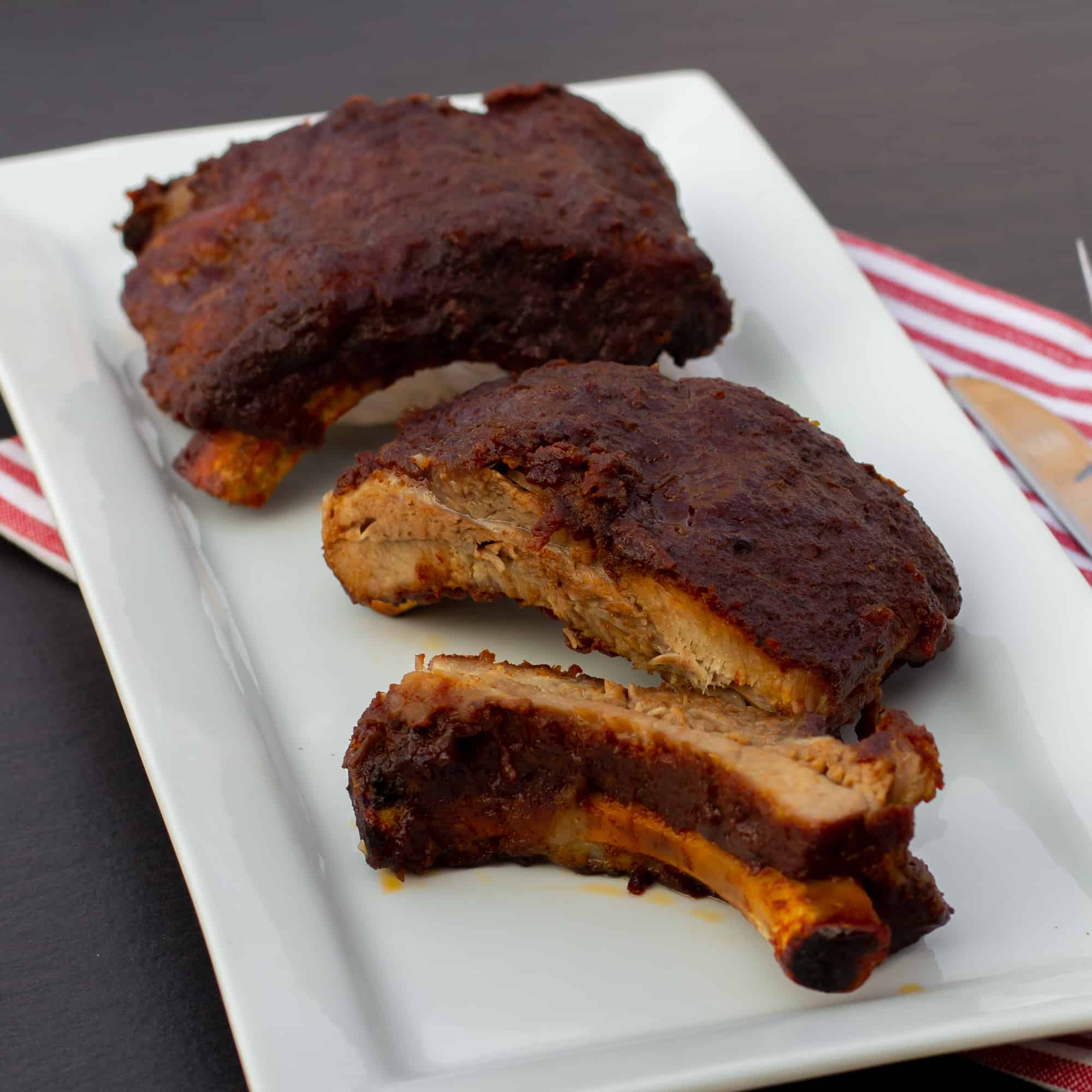 Slow braised ribs with rub and bourbon bbq sauce recipe. Cook in the oven or crock pot / slow cooker. Meat is fall off the bone tender.