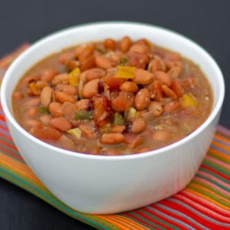 Slow cooked pinto beans with ham hock, tomato, onion, jalapeno and ancho chilies. Amazing tex-mex / Mexican comfort food baked bean recipe made in a Crock Pot.