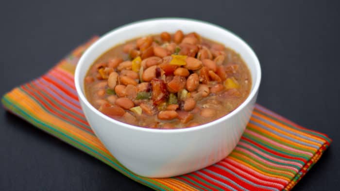 Slow cooked pinto beans with ham hock, tomato, onion, jalapeno and ancho chilies. Amazing tex-mex / Mexican comfort food baked bean recipe made in a Crock Pot.