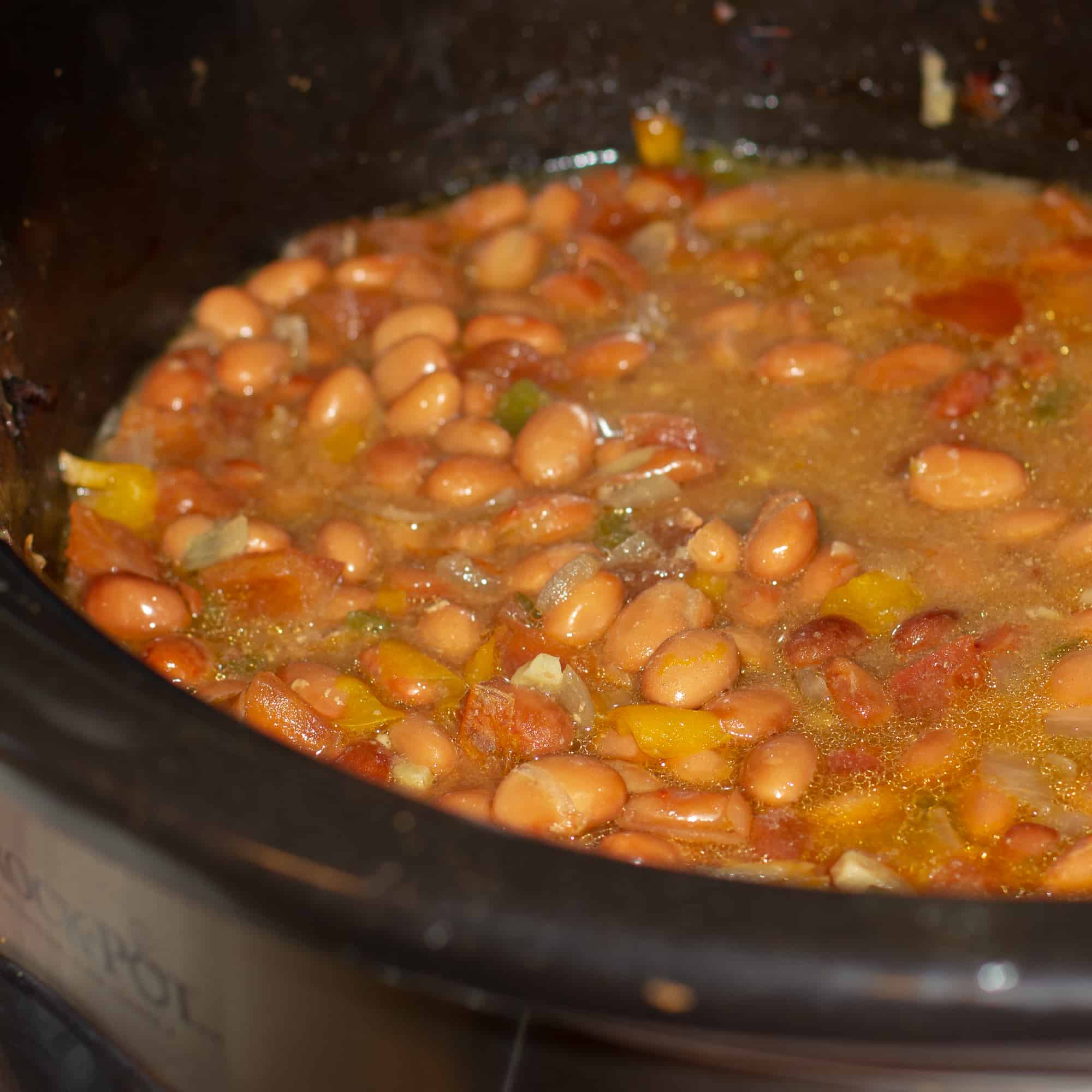 Slow cooked pinto beans with ham hock, tomato, onion, jalapeno and ancho chilies. Amazing tex-mex / Mexican comfort food baked bean recipe made in a Crock Pot.
