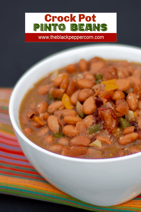 Slow cooked pinto beans with ham hock, tomato, onion, jalapeno and ancho chilies. Amazing tex-mex / Mexican comfort food baked bean recipe made in a Crock Pot.