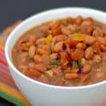 Slow cooked pinto beans with ham hock, tomato, onion, jalapeno and ancho chilies. Amazing tex-mex / Mexican comfort food baked bean recipe made in a Crock Pot.