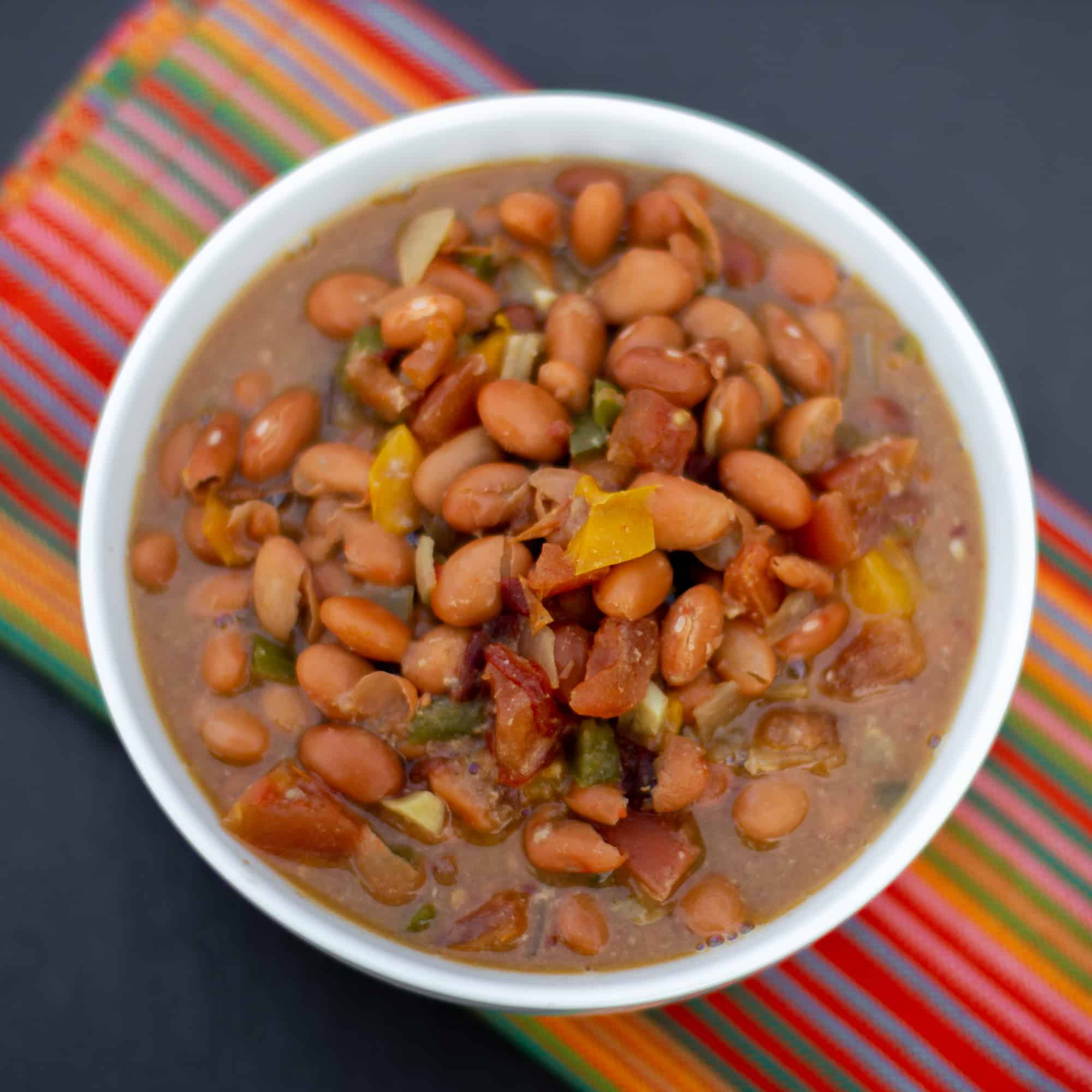 Slow cooked pinto beans with ham hock, tomato, onion, jalapeno and ancho chilies. Amazing tex-mex / Mexican comfort food baked bean recipe made in a Crock Pot.