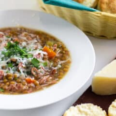 A warm bowl of soup with fresh baked biscuits.