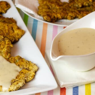 I gravy boat with a plate of country fried steak.