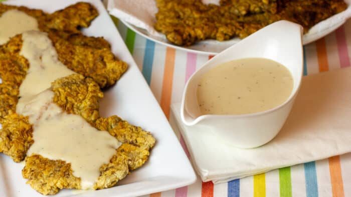 I gravy boat with a plate of country fried steak.