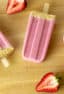 Three popsicles with halved strawberries all around them.