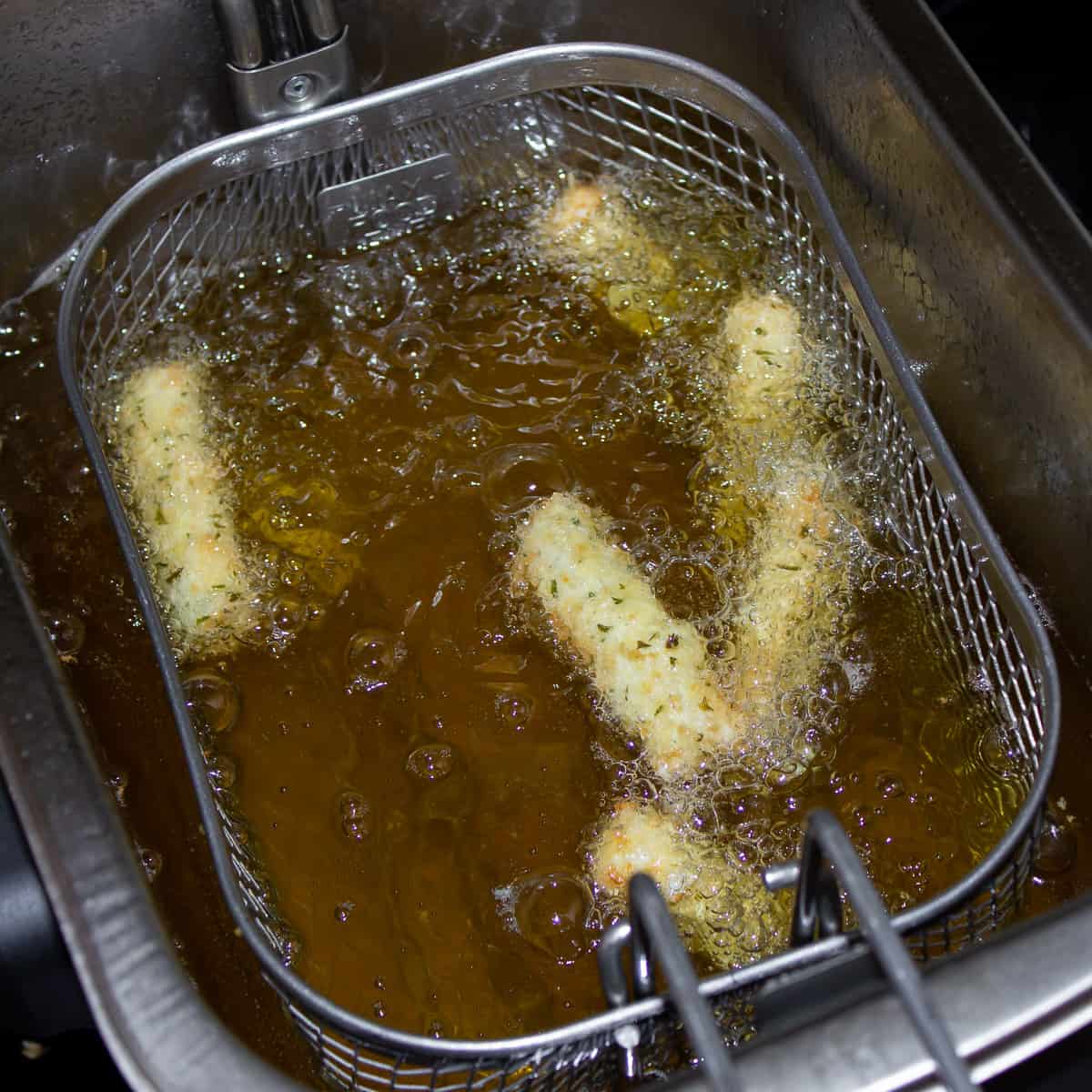 A deep fryer with bread sticks in the hot oil