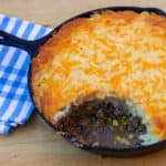 How to make shepherd's pie in a cast iron skillet! Baked recipe has beef filling with peas and corn, topped with mashed potatoes and grated cheddar cheese.