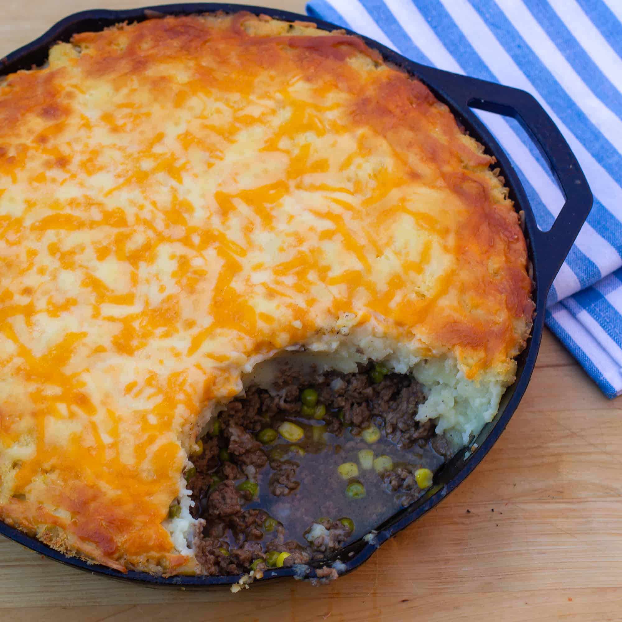How to make shepherd's pie in a cast iron skillet! Baked recipe has beef filling with peas and corn, topped with mashed potatoes and grated cheddar cheese.
