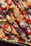 Nachos made with smoked brisket, provolone cheese, onions, peppers baked on tortilla chips with BBQ sauce. Simple party food that is smokey and delicious!