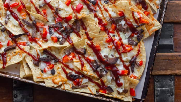 Nachos made with smoked brisket, provolone cheese, onions, peppers baked on tortilla chips with BBQ sauce. Simple party food that is smokey and delicious!