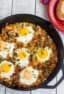 An overhead image of baked eggs in a cast iron skillet.