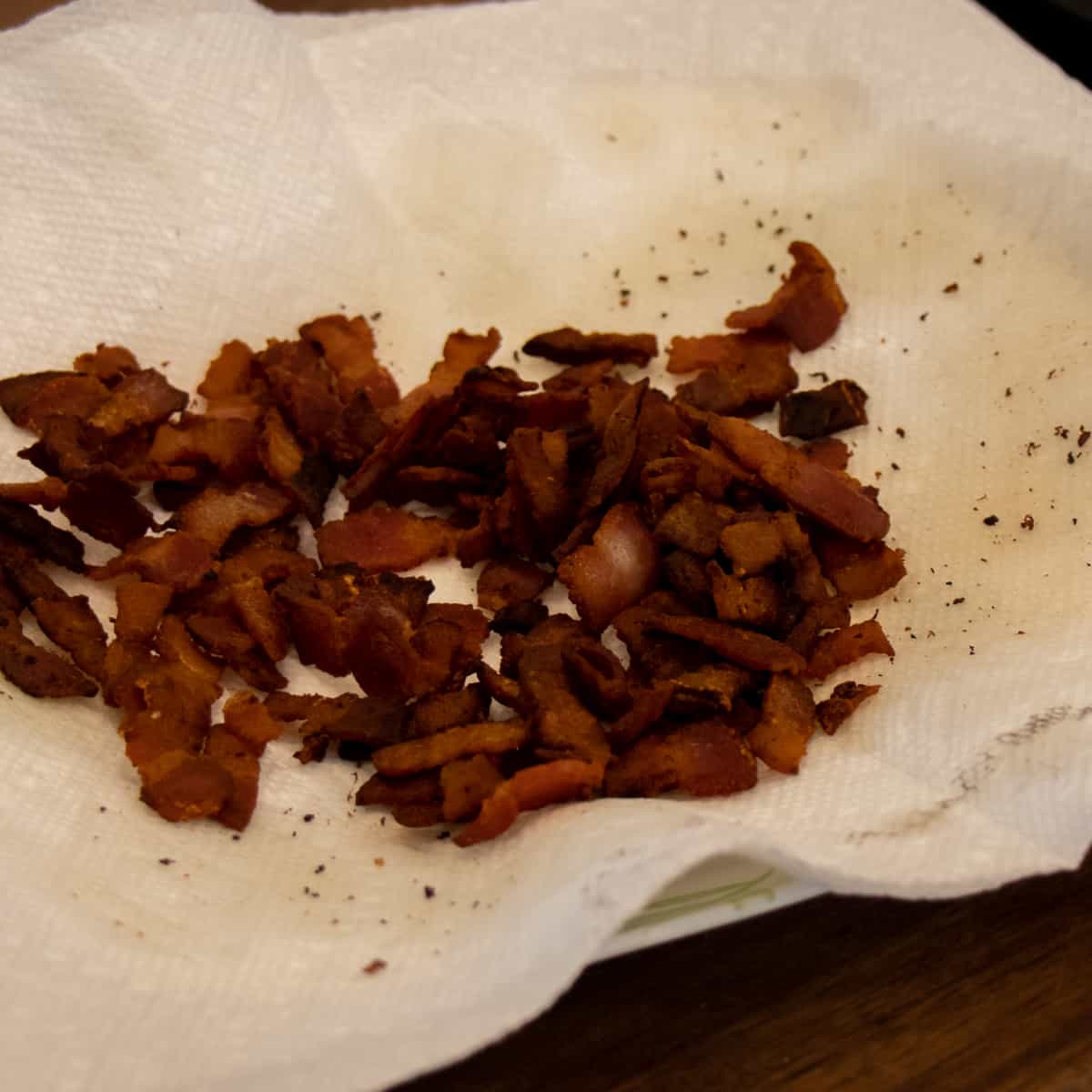 Fried bacon draining on a paper towel.