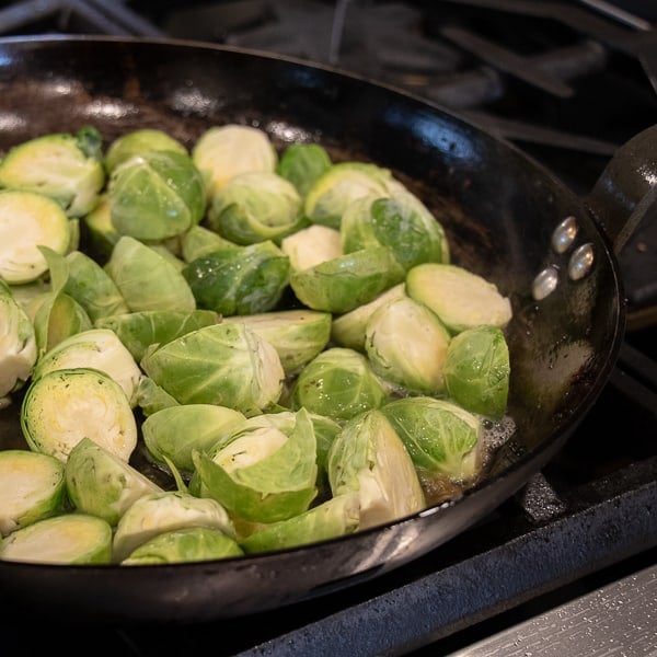 Pan Fried Brussels Sprouts with Bacon - How to cook brussels sprouts in a pan on the stove with crumbled bacon and crispy fried onions using this simple recipe. A delicious side dish with browned caramelized brussels sprouts that taste similar to being roasted.