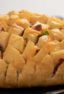 Cheesy pull apart bread made with an artisan rustic round bread loaf, sliced and filled with grated cheddar cheese, crumbled bacon and sliced green onions. Baked until cheese is bubbly!