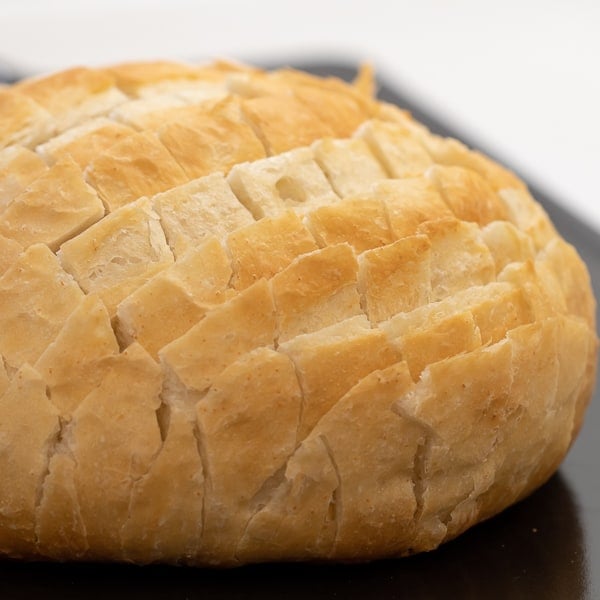 Cheesy pull apart bread made with an artisan rustic round bread loaf, sliced and filled with grated cheddar cheese, crumbled bacon and sliced green onions. Baked until cheese is bubbly!