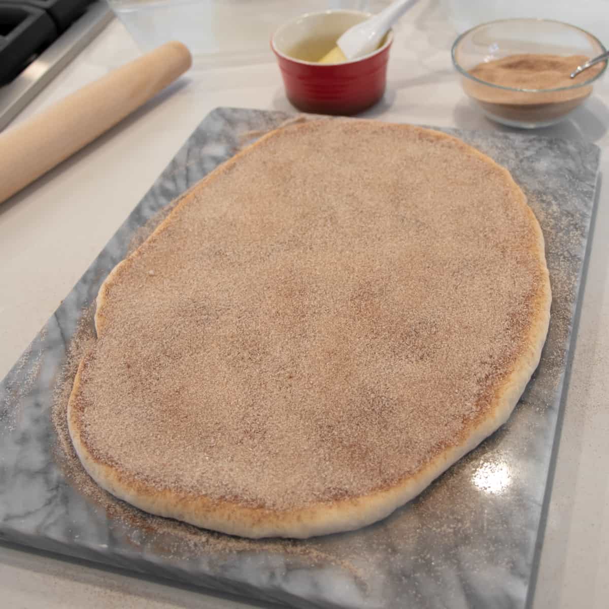 Cinnamon sugar sprinkled on rolled out bread dough.