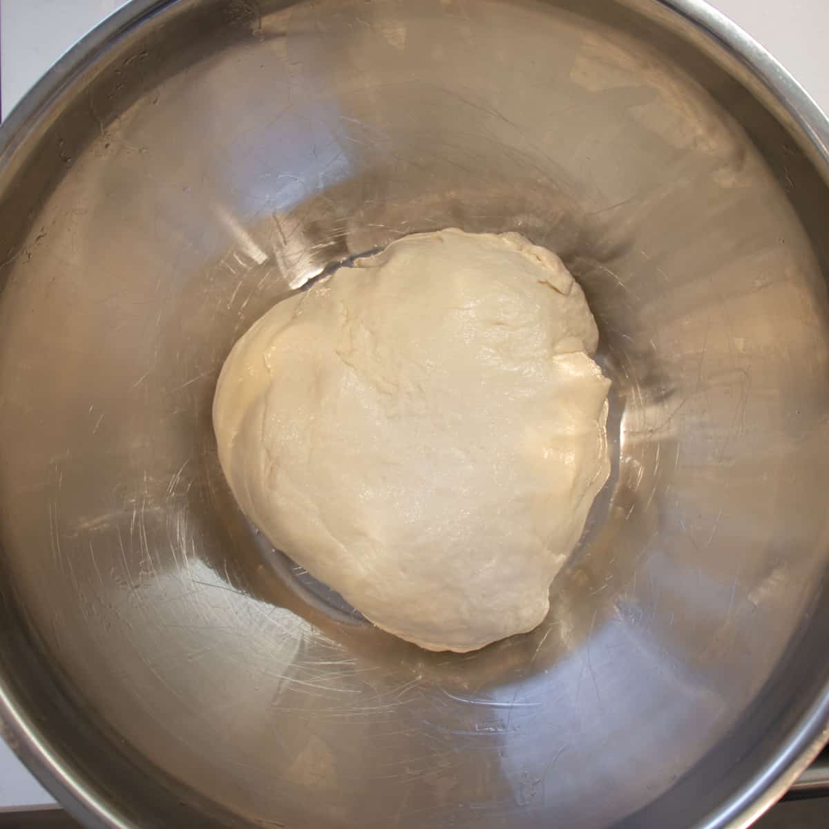 Bread dough in a large metal bowl before rising.