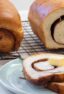 Sliced bread on a plate in front of two loaves on a wire rack.